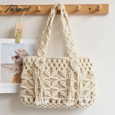 a white crocheted purse hanging on a wooden hanger next to a magazine