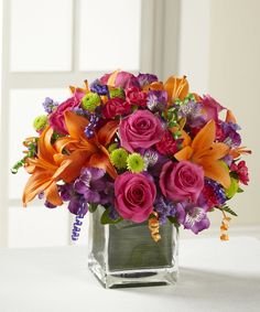 a square vase filled with colorful flowers on top of a table