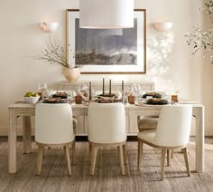 a dining room table set for four with white chairs