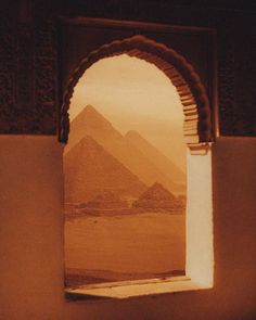 an arch opening into a desert with the pyramids in the background