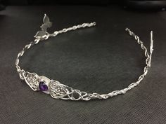 I've fabricated a true Celtic inspired bridal wedding circlet with ornate woven knot extensions holding a center 10mm round Amethyst cabochon gemstone. The circlet is entirely in sterling silver. I've added luxurious detailing around the center stone with four ivy leaves, two on each side, so that the weaves of Celtic knotwork, intertwine with the wires of silver braiding, in and out, throughout the headpiece and leaf work. For a matching pendant necklace, also set with an 8mm gemstone, can be f Handmade Round Crown Wedding Headpieces, Handmade Wedding Headpieces With Round Crown, Handmade Teardrop Crown Jewelry For Wedding, Handmade Adjustable Headband For Weddings, Handmade Wedding Jewelry Headband, Handmade Teardrop Crown Headpiece For Weddings, Handmade Adjustable Headpieces For Wedding, Adjustable Handmade Headpieces For Wedding, Traditional Adjustable Wedding Headband