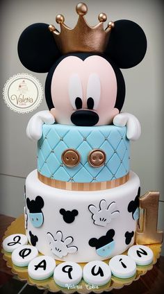 a mickey mouse cake is decorated with blue and white icing, gold trimmings