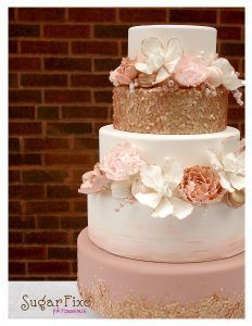 a three tiered wedding cake with flowers on top