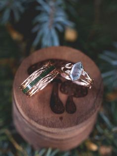 A matching wedding ring set from Staghead Designs sits on a custom mushroom engraved ring box. These rings in our "Artemis" designs include a 14K rose gold wedding band that has antler/branch-like metal work & a centered moss inlay. On the right is the "Artemis" engagement ring with an antler/branch-like 14K rose gold band, diamond accents, & an elongated hexagon cut moss agate center stone. These rings can also be made in white or yellow gold & with a variety of unique stones & inlay materials. Moss Agate Wedding Rings, Agate Wedding Rings, Whiskey Barrel Wedding Ring, Antler Wedding Rings, Matching Wedding Ring Sets, Nature Wedding Ring, His And Her Wedding Rings, Agate Wedding Ring, Nontraditional Engagement Rings