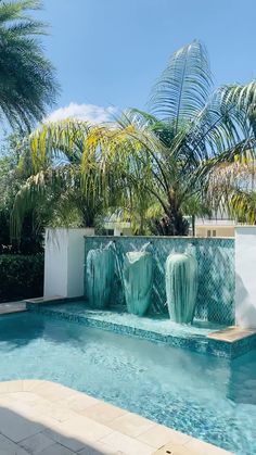 an empty swimming pool surrounded by palm trees and water features in the middle of it