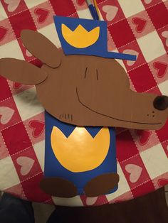 a paper cut out of a dog with a crown on its head sitting on a red and white checkered tablecloth