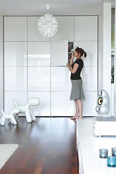 a woman standing in the middle of a room with white walls and wood flooring