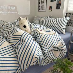 a bed with blue and white striped comforters, pillows and a stuffed animal on it