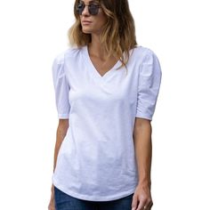 Introducing the Amaryllis Women's V-Neck Puff Sleeve Tee, where casual meets elegance. This tee features a flattering V-neckline that enhances the neckline, while the puff sleeves with gathered shoulder detail add a stylish and feminine touch. Made from soft stretch fabric, this tee provides comfort and ease of movement, making it an ideal choice for everyday wear. The relaxed fit ensures it pairs effortlessly with jeans or skirts for a versatile look. Whether you're running errands or meeting f Casual Short Sleeve V-neck Top For Brunch, White V-neck Puff Sleeve Top For Day Out, Casual V-neck Cotton Puff Sleeve Top, Feminine Cotton Puff Sleeve Top With V-neck, Cotton V-neck Puff Sleeve Top For Brunch, White V-neck Puff Sleeve Top For Brunch, Chic V-neck Puff Sleeve Top For Day Out, White V-neck Top For Casual Gatherings, Trendy V-neck Puff Sleeve Top For Spring