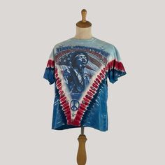 Step into the music scene with this Vintage Jimi Hendrix American Flag Blues Guitarist Tie Dye Tee. Officially licensed and medium-sized, this shirt is a genuine tribute to the legendary guitarist. Its tie-dye pattern with the American flag motif channels the hippie vibes of the era. Ideal for music enthusiasts, collectors, and those who appreciate vintage fashion, this tee is more than apparel; it's a piece of concert memorabilia representing a crucial moment in music history. Whether you're a Blues Guitarist, Hippie Vibes, Graphic Tees Vintage, Tie And Dye, Music History, Tie Dye Patterns, Tie Dye T Shirts, Hendrix, Mode Vintage