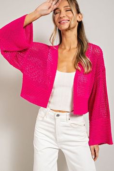 a woman in white pants and a pink cardigan