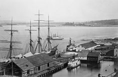 an old black and white photo of a harbor with ships in the water next to buildings