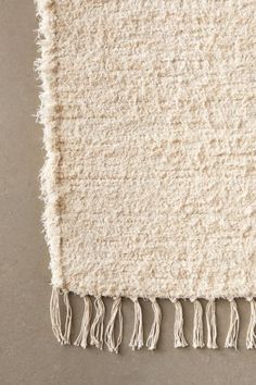 a white rug with fringes on the bottom and one piece of yarn hanging from it