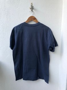 a blue t - shirt hanging on a white wall next to a wooden hanger