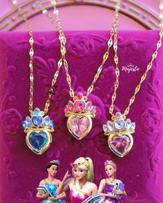 three necklaces with princesses on them are hanging from a pink velvet case,