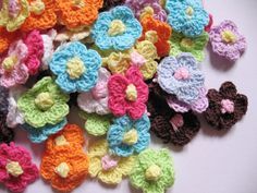 crocheted flowers are arranged on a white surface with brown, yellow, and blue petals