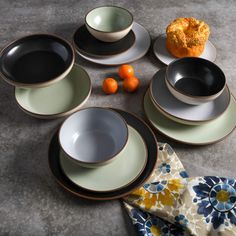 a table topped with plates and bowls next to an orange on top of a napkin