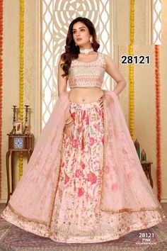 In a whisper of romance, the blush pink lehenga choli set blooms with bold floral patterns that burst across the fabric. Each flower, embroidered with meticulous detail, speaks of elegance and vitality, creating a vibrant tapestry. The embroidered border adds a touch of intricate charm, framing the bold blooms with delicate artistry. Adorned in this ensemble, she embodies a perfect blend of soft allure and striking beauty, radiating grace with every step. * Pre stitched lehenga for women. * Crafted from a Georgette fabric for luxurious feel and touch. * The blouse features sequin embroidery throughout. * The sleeveless blouse features back opening with hook closure and tie ups * Dry clean or hand wash for longer life. Note: Colors may slightly vary due to photographic l Pink Floral Print Lehenga For Wedding, Designer Pink Anarkali Set With Floral Print, Pink Anarkali Sharara With Floral Embroidery, Pink Fitted Sharara With Floral Embroidery, Pink Floral Print Reception Dress, Pink Floral Print Dress For Reception, Pink Bollywood Choli With Floral Print, Bollywood Style Pink Floral Choli, Fitted Pink Floral Anarkali Set