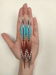 a hand holding a pair of beaded earrings