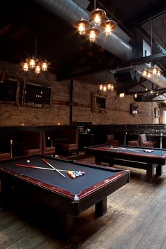 an indoor pool table with lights hanging from the ceiling