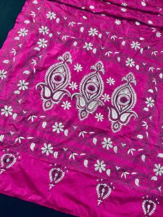 a pink cloth with white flowers and paisleys on it, laying on a black surface