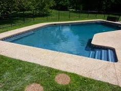 an empty swimming pool surrounded by green grass