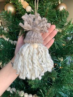 a hand holding a knitted ornament on top of a christmas tree