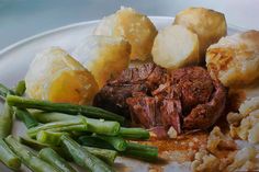 a white plate topped with meat, potatoes and green beans