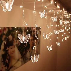 some lights hanging from the ceiling in a room with pictures on it and butterflies attached to them