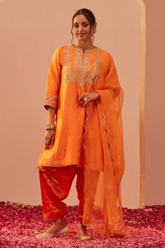 Tangerine orange short choga with tilla, patra, foil mirror embroidery in paisley pattern. Paired with floral hand block print salwar and dupatta.
Components: 3
Pattern: Embroidery, Hand Block Printed
Type Of Work: Tilla, patra, foil mirror, floral
Neckline: Round
Sleeve Type: Three quarter
Fabric: Kurta: Silk Chanderi, Salwar: Bamberg Satin, Dupatta: Silk Organza
Color: Orange
Other Details: 
Front embellished buttons
Cutwork border
Mughal bordered printed sheer dupatta
Occasion: Sangeet - Aza Satin Dupatta, Sheer Dupatta, Embellished Buttons, Blouse Yoke, Notes Craft, Mirror Embroidery, Personal Shopping Service, Embroidery Hand, Tangerine Orange