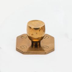 a brass plated object on a white surface with two holes in the middle and one hole at the top