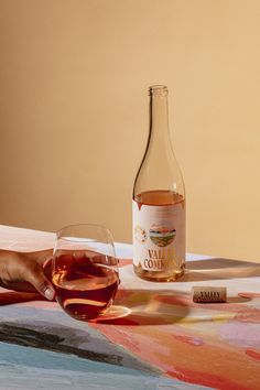 a bottle of wine sitting on top of a table next to a glass filled with liquid