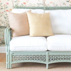 a white couch with pillows on it in front of a floral wallpapered wall