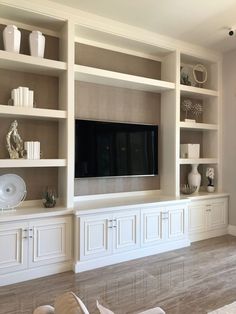 a living room with white bookcases and a flat screen tv on the wall