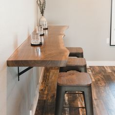 a wooden table with two stools in front of it and a vase on top