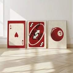 three red and white playing cards sitting on top of a hard wood floor next to a window