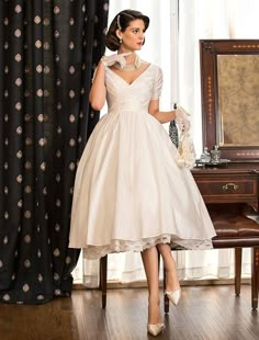 a woman standing in front of a mirror wearing a white dress