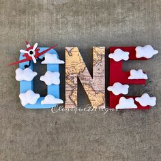 the letters are made out of wood and painted red, white, and blue with clouds