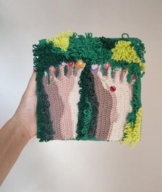 someone is holding up a crocheted handbag with green and pink designs on it