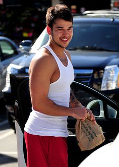 a man standing next to a car holding a bag