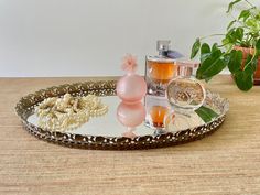 an assortment of perfumes and flowers on a decorative tray next to a potted plant