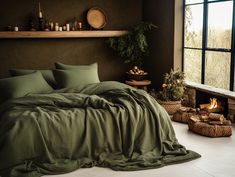 a bed with green sheets and pillows in front of a window next to a fire place