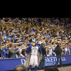 a man in a blue and white uniform standing on a basketball court with his hands up