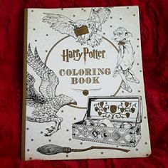 the harry potter coloring book is laying on a red bed sheet with an owl flying next to it