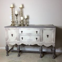 an old dresser with candles on top and two smaller ones sitting on the sideboard