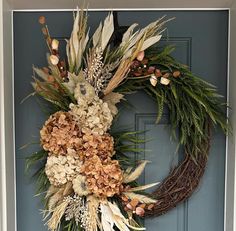 a wreath with dried flowers and foliage is hanging on the front door's blue door