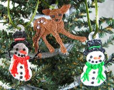 three ornaments hanging from a christmas tree decorated with snowmen and reindeers on them