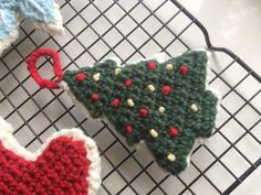 three crocheted christmas tree ornaments sitting on a wire rack next to each other