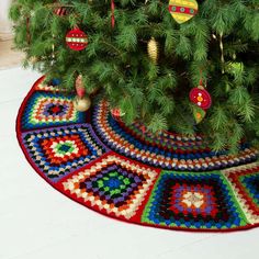 a christmas tree with ornaments hanging from it's branches in front of a rug