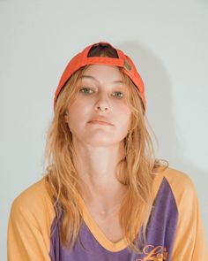 a woman with long hair wearing an orange and purple shirt is looking at the camera